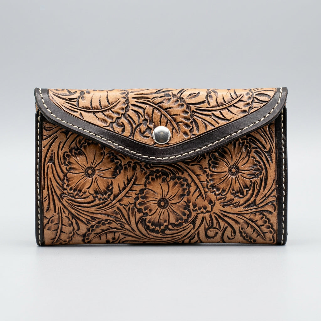 A brown tooled leather wallet with floral hand tooled and black trim.