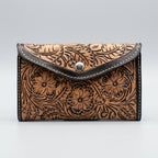 A brown tooled leather wallet with floral hand tooled and black trim.
