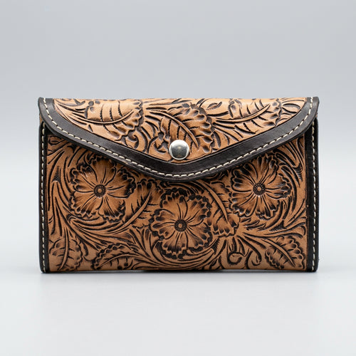 A brown tooled leather wallet with floral hand tooled and black trim.